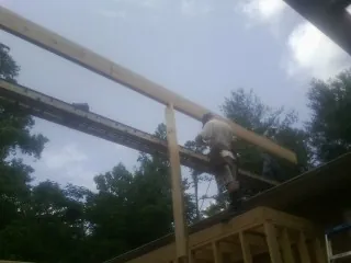 Carpenter setting a ridge beam over a new addition frame — Ice Dam Removal by Roofing Brothers in Moss