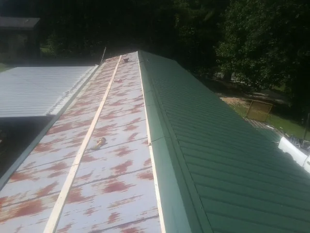 Old rusted panels beside newly installed green metal roofing — Wind Damage Roof Repair by Roofing Brothers in Moss