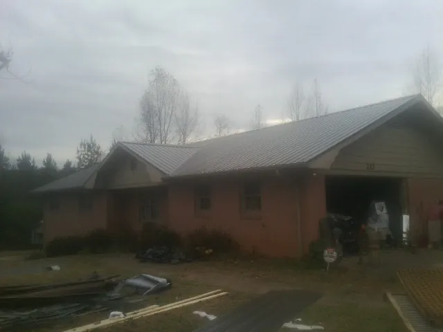 Gray metal roof on a stucco house with an attached garage in Moss