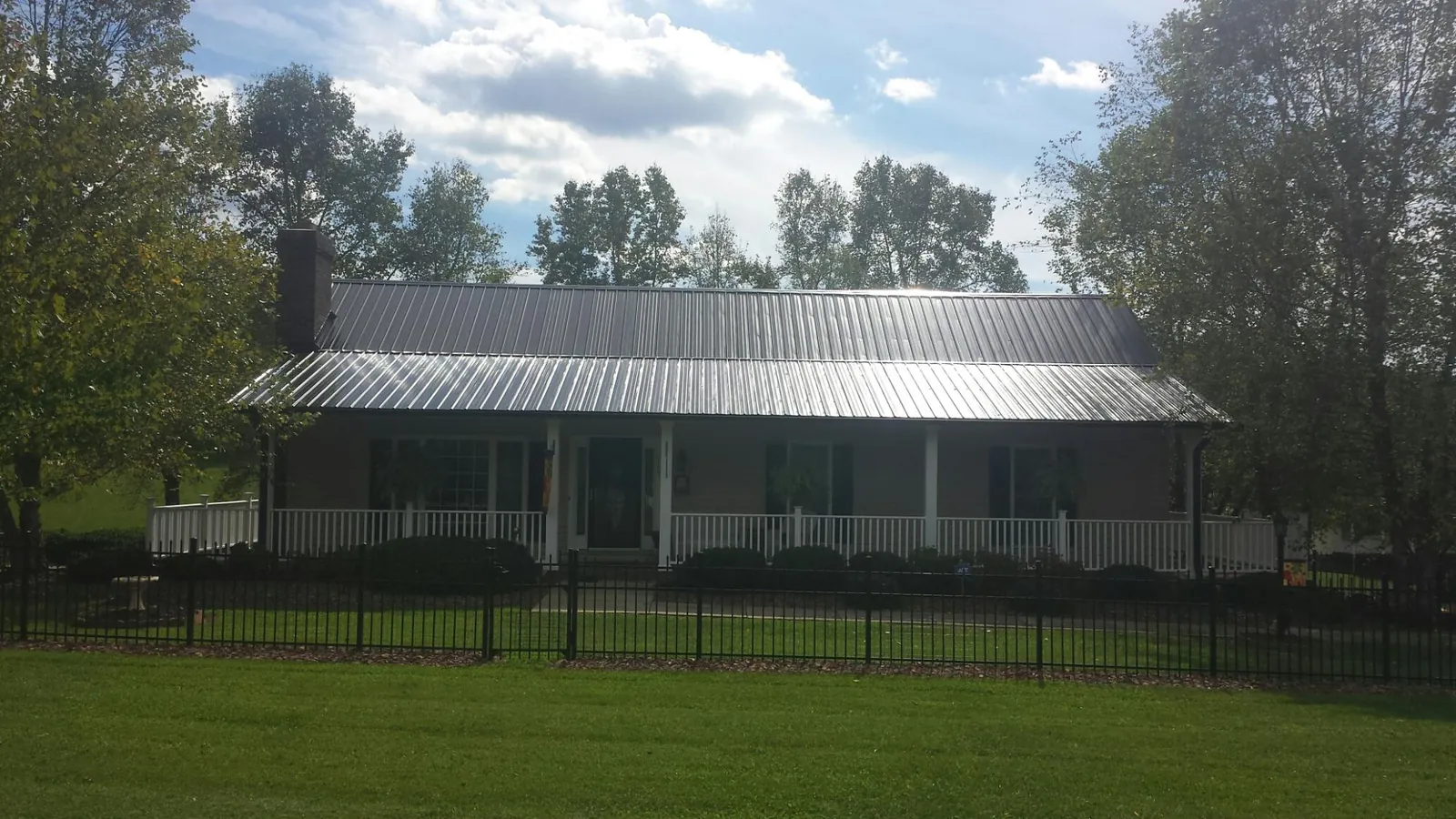 Gray metal roof on a brick ranch with a full width front porch — Gutter Guard Installation work by our crew in Moss