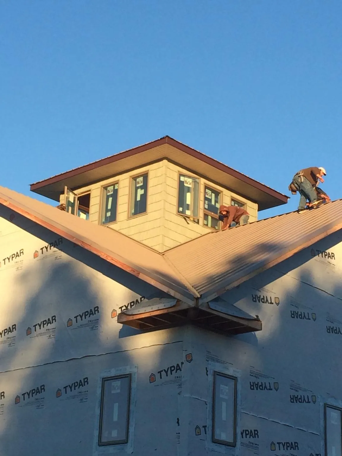 Roofers working around a rooftop cupola on a new metal roof at sunset — Roof Waterproofing in Moss by Roofing Brothers